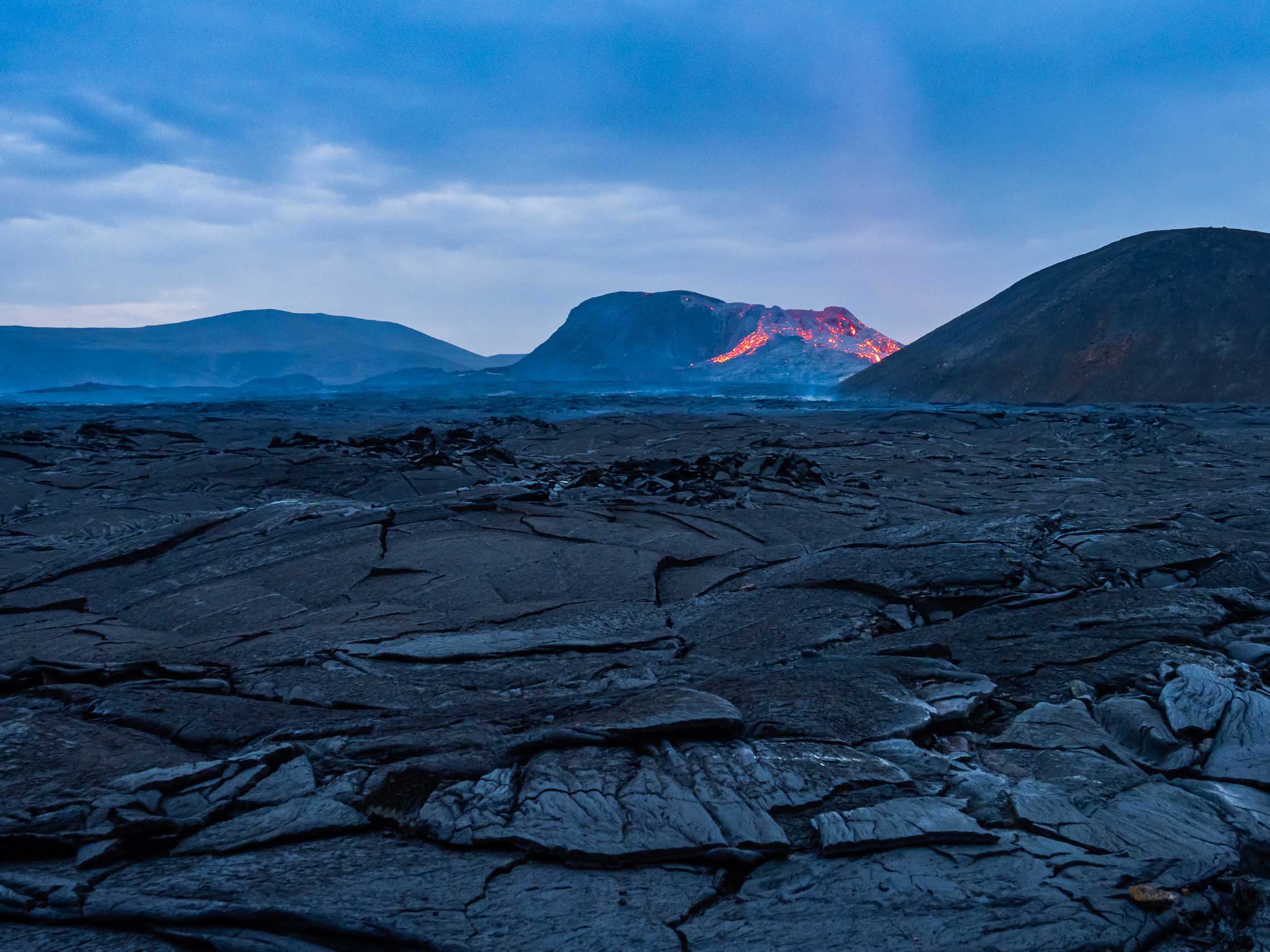 Fresh lava oozing out from under black slabs in Iceland