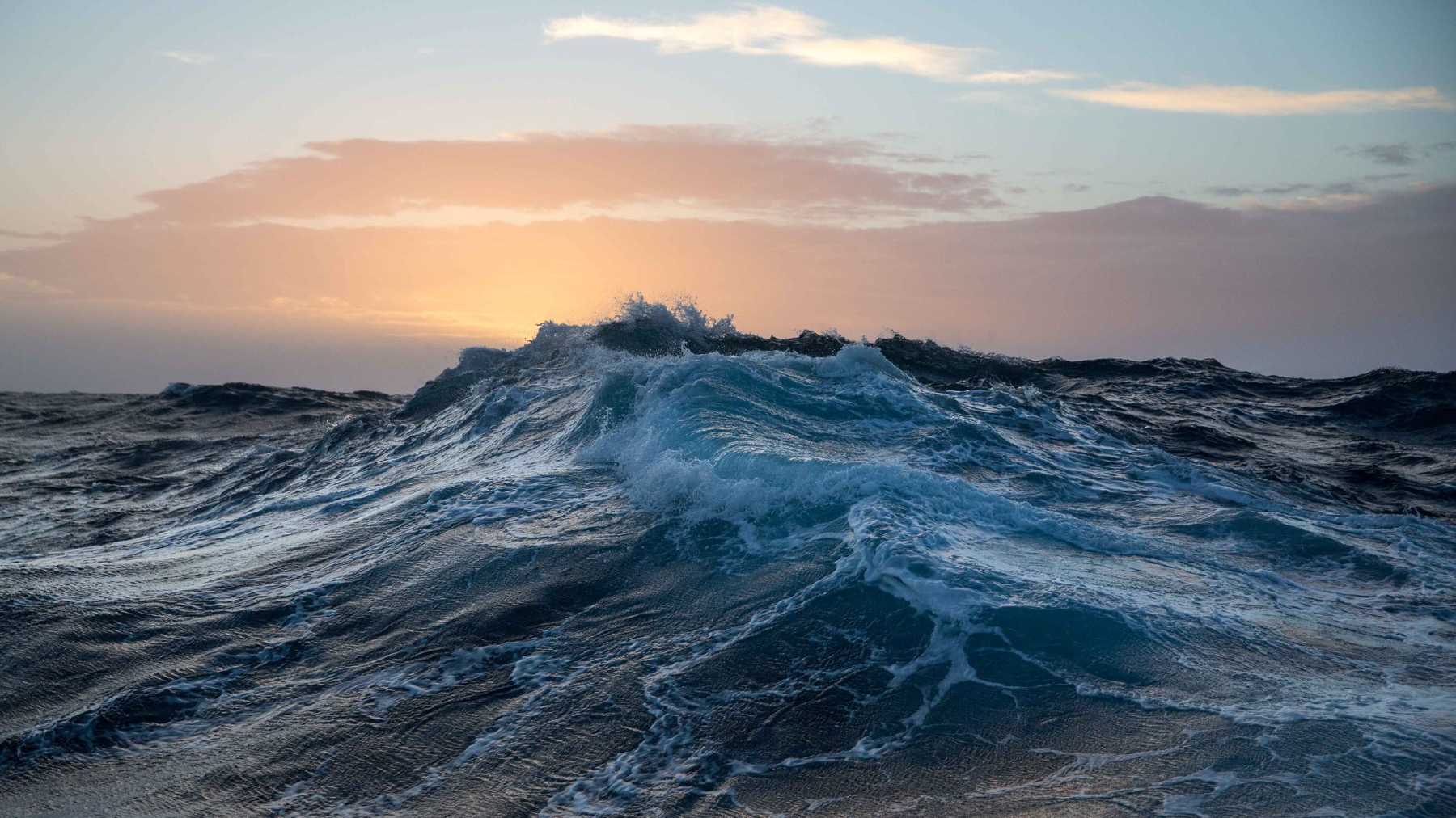 At sunrise; a dark, roiling sea, streaked with spume