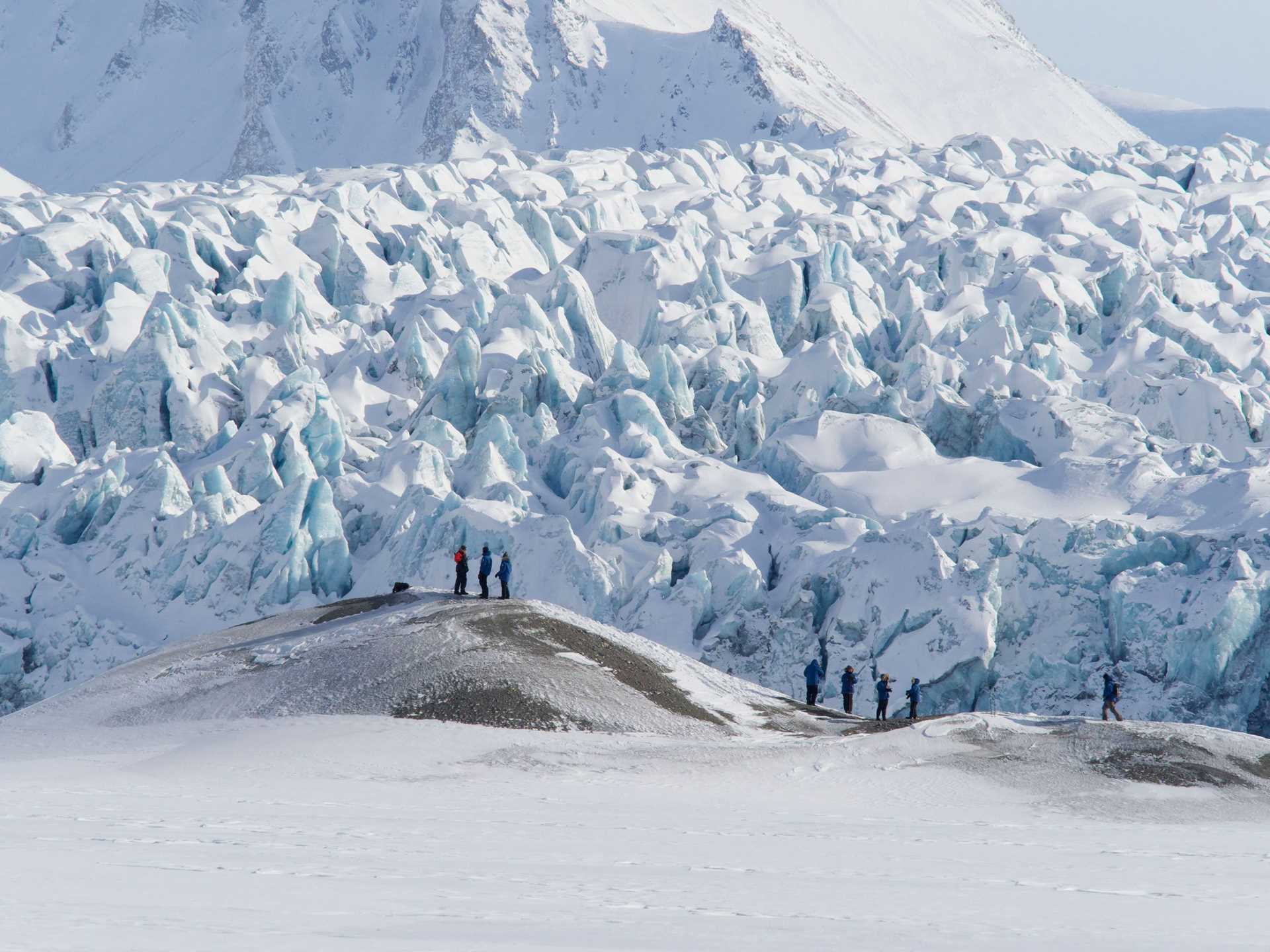 hikers in front of a massive glacier